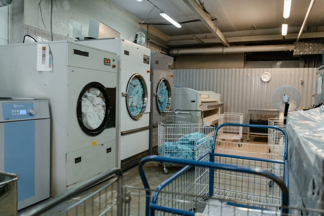 Machines à laver et sécher industrielles dans une laverie professionnelle, avec des chariots à linge